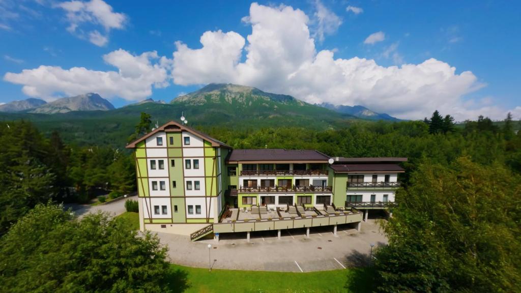 a large building with a balcony in front of mountains at Apartmanovy dom Familia Smokovec in Starý Smokovec