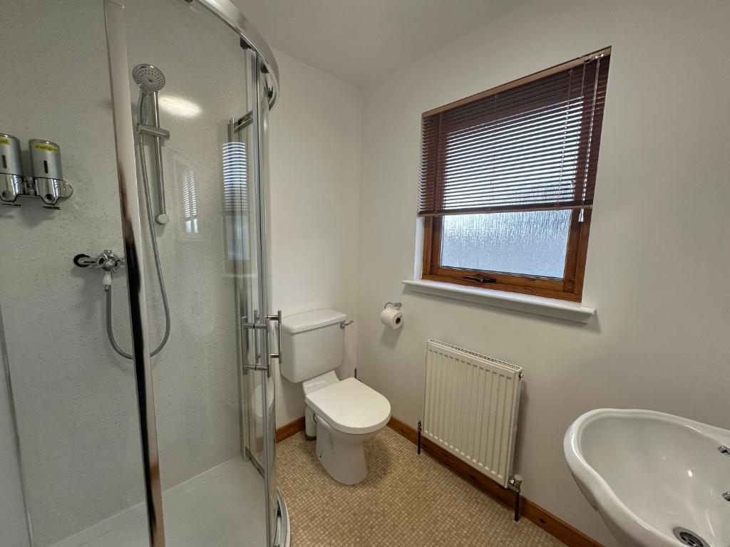 a bathroom with a shower and a toilet and a sink at Benlochy Cottage in Fort William