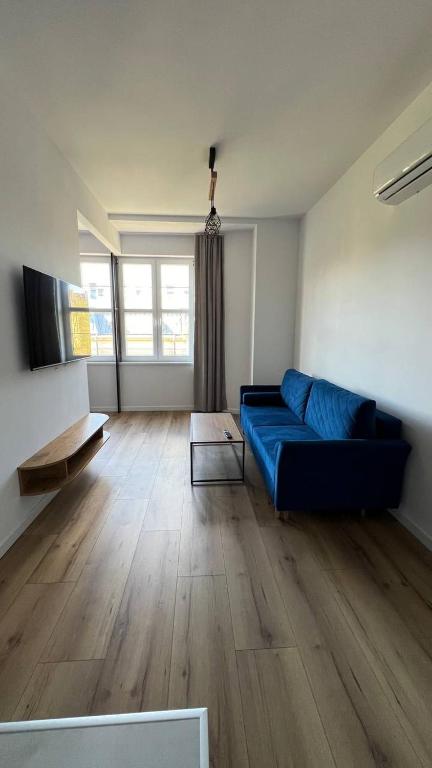 uma sala de estar com um sofá azul e piso em madeira em CityCenterApartments/M32/8B em Bielsko-Biala