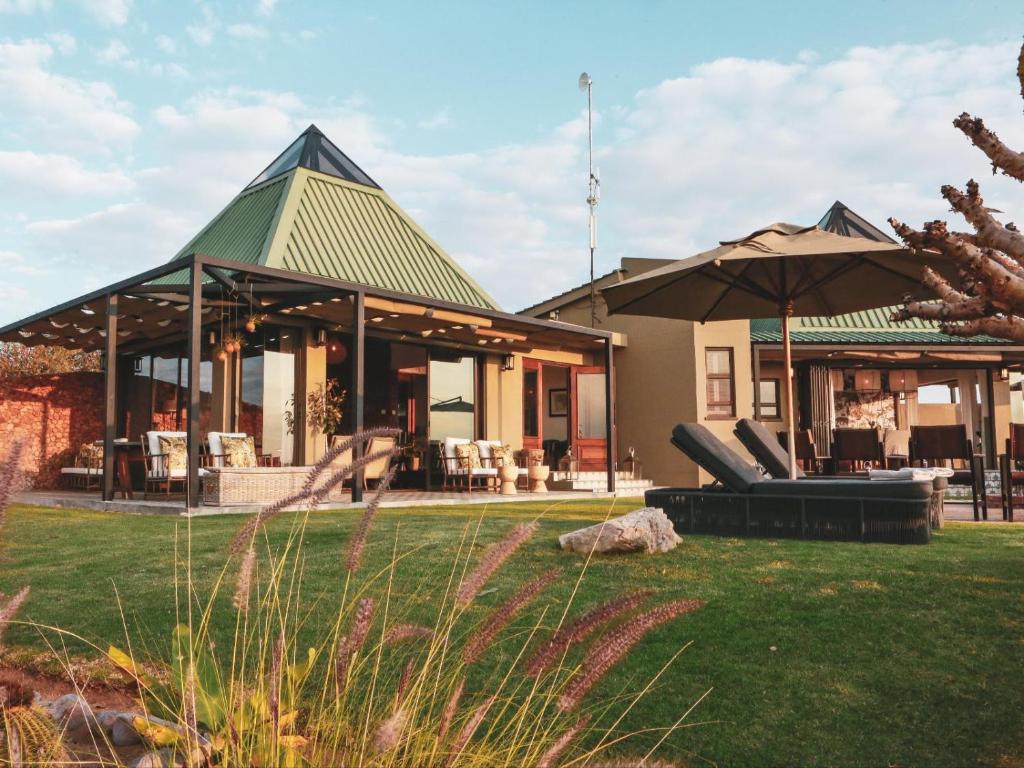 a house with a green roof with a patio at Otjiwa Mountain Lodge in Otjiwarongo