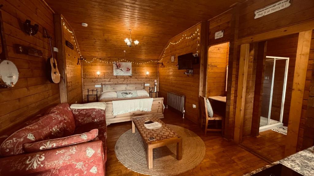 una sala de estar con sofá y una cama en una cabaña en Blossom Cabin - Little log Cabin in Wales en Newtown