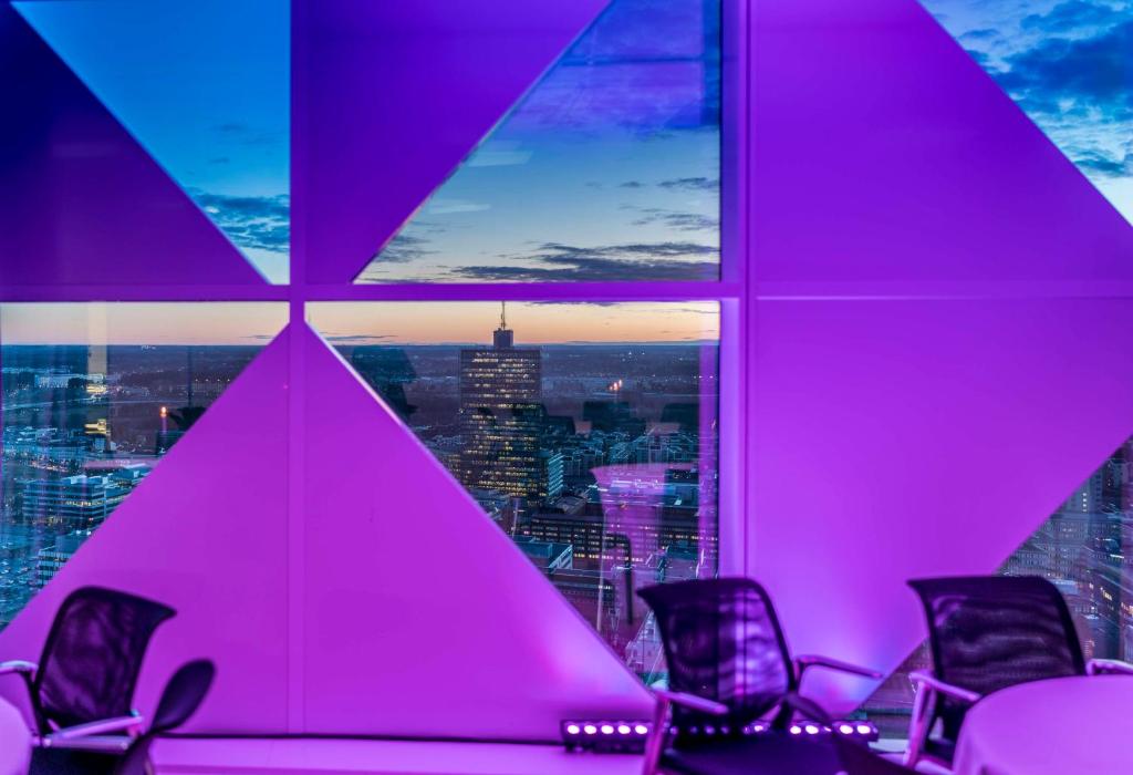 ストックホルムにあるスカンディック ビクトリア タワーの椅子とピンクの照明付きの窓が備わる客室です。