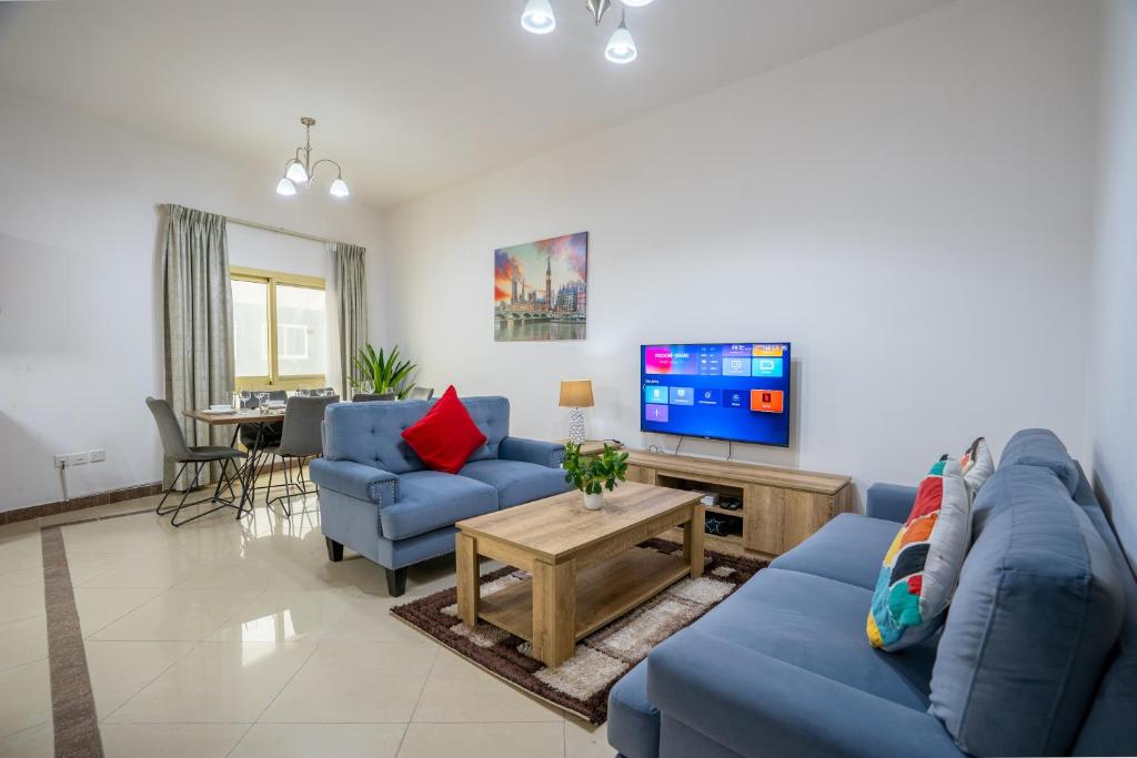 a living room with a blue couch and a tv at RH- Experience Comfort and Convenience in our 2BR, Al Barsha in Dubai