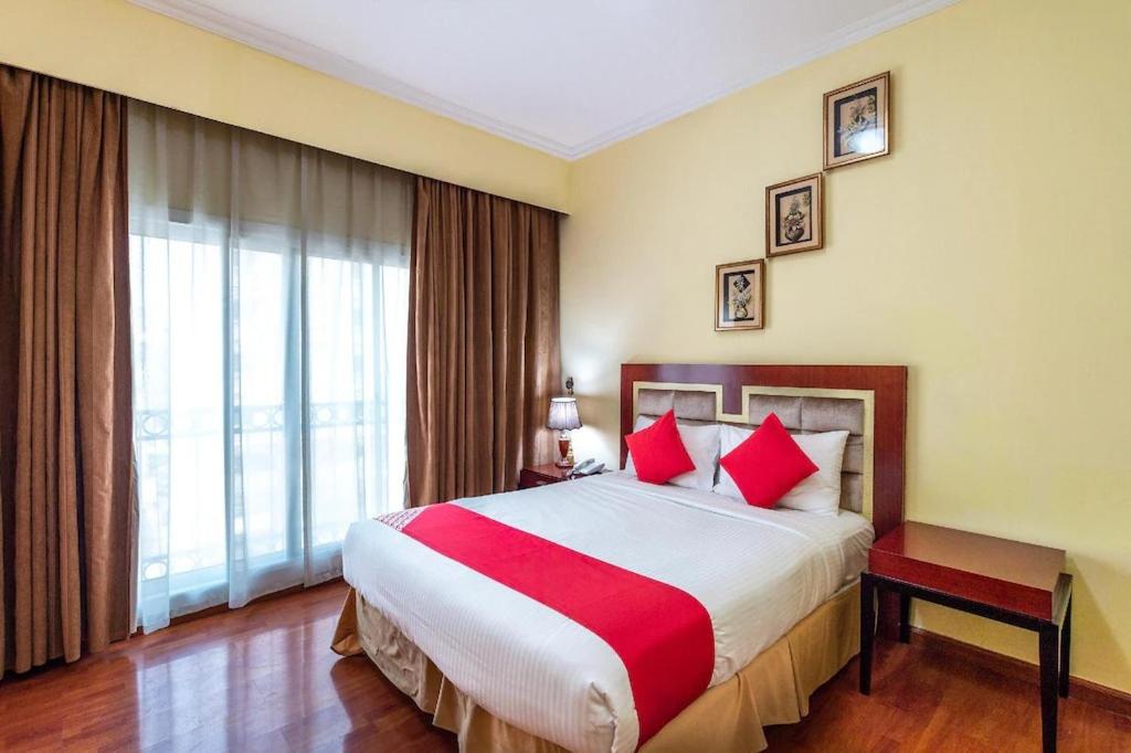 um quarto de hotel com uma cama grande com almofadas vermelhas em Zenith Smart Vacation Homes, Sharjah em Sharjah