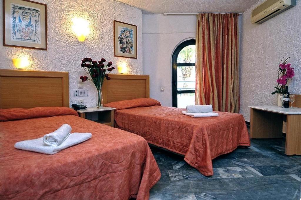 a hotel room with two beds with towels on them at Karteros Hotel in Karteros