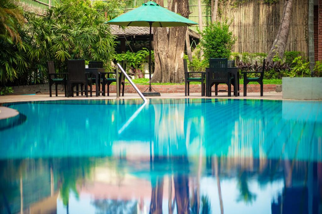 a swimming pool with chairs and an umbrella at ANGKOR TRAILS Residence in Siem Reap