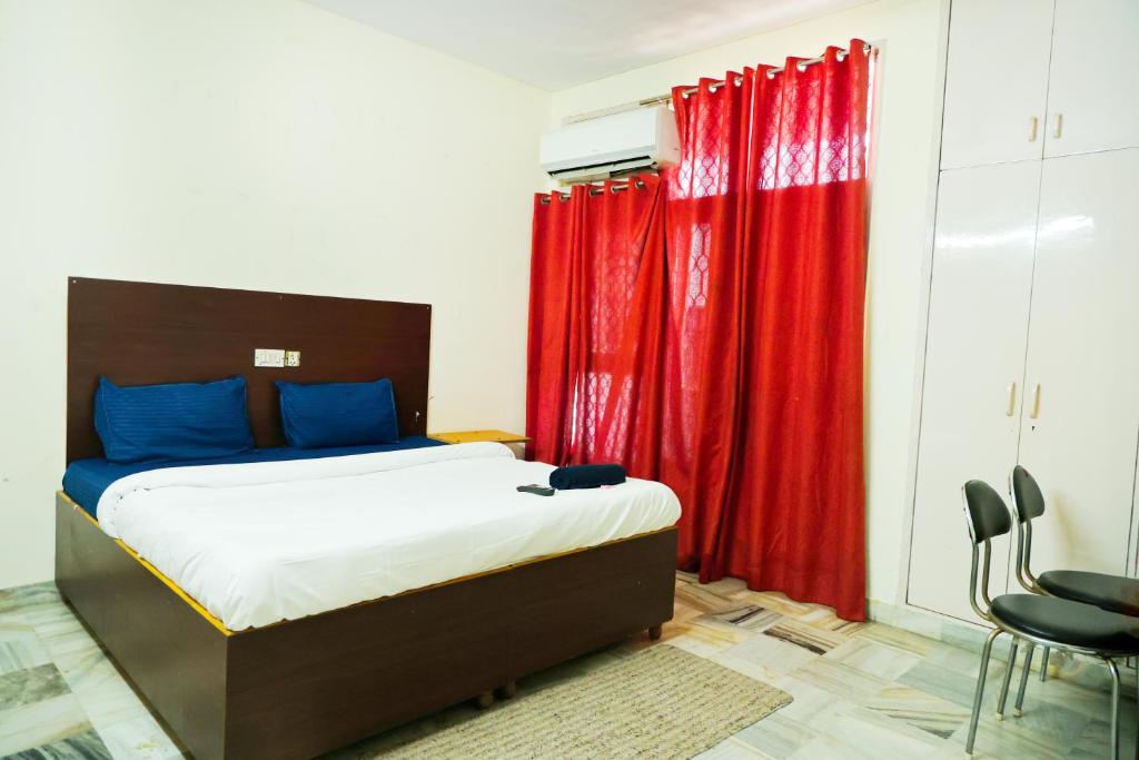 a bedroom with a bed with red curtains at Hotel Green Villa - Near Anand Vihar Railway Station in New Delhi