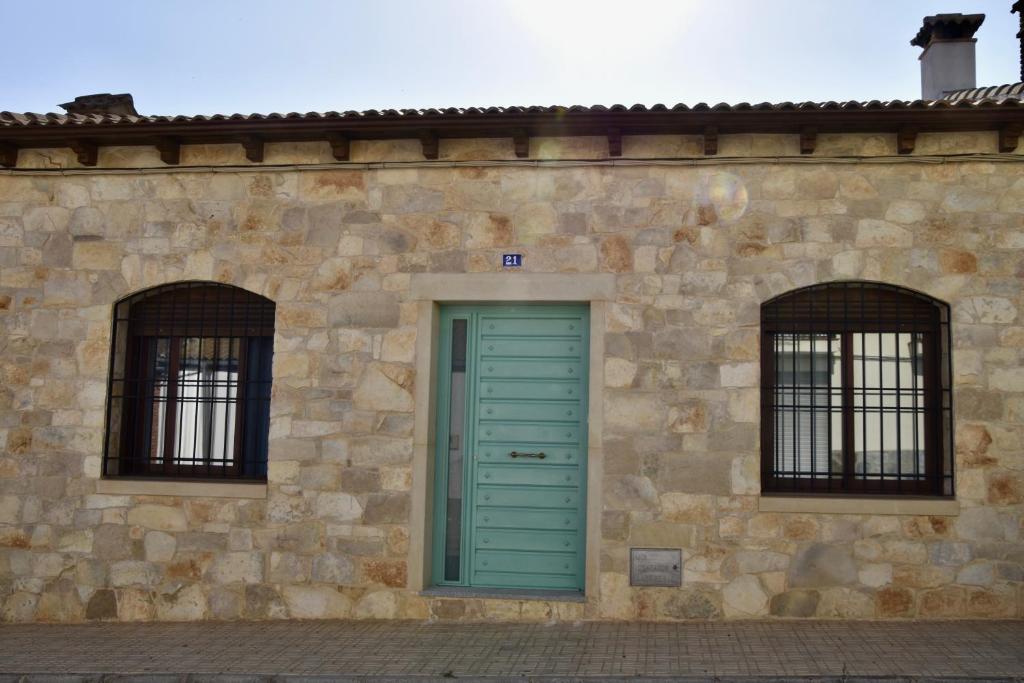 - un bâtiment en pierre avec une porte verte et 2 fenêtres dans l'établissement Casa Rural, El Retorno, à Santa Elena