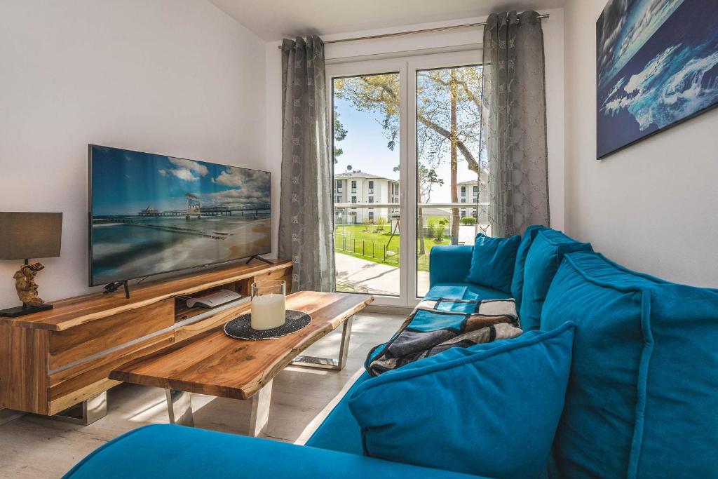 a living room with a blue couch and a tv at An der Haffküste Meerzeit in Zirchow