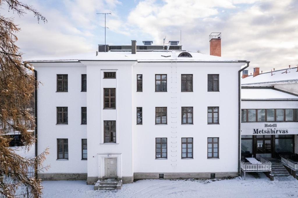 a white building in the snow at Hotel Metsähirvas in Rovaniemi