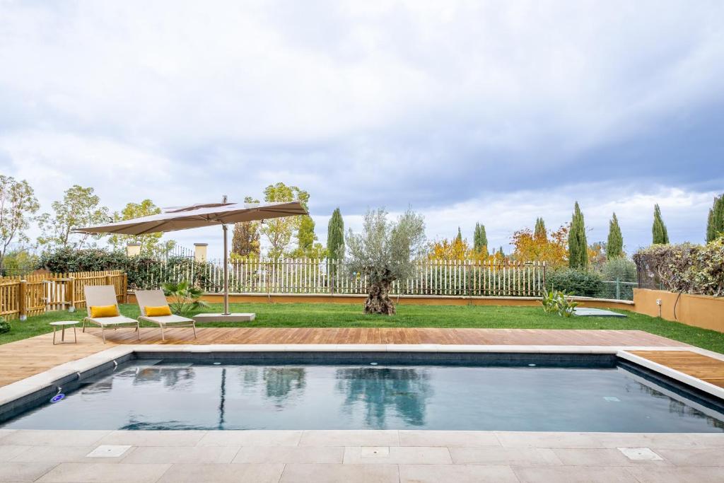 einen Pool in einem Garten mit zwei Stühlen und einem Sonnenschirm in der Unterkunft aura in Monte Porzio Catone