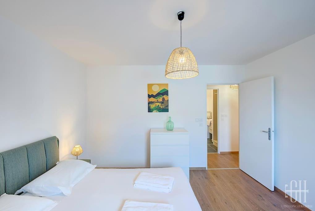 een witte slaapkamer met een bed en een hanglamp bij L'ardoise / Proche Centre in Fondettes
