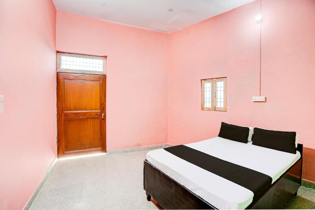 a bedroom with a bed and a wooden door at SPOT ON THE SWEET DREAM HOTEL in Alīgarh
