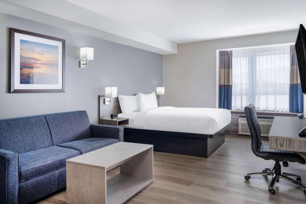 Microtel Inn & Suites by Wyndham Kanata Ottawa West في كاناتا: غرفه فندقيه بسرير واريكه