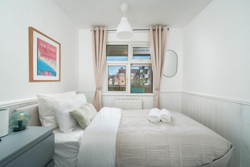 una camera da letto bianca con un letto e asciugamani di Gorgeous 3 Bedroom flat In London on Central Line for Families, Contractors, Business Travellers a Woodford Green