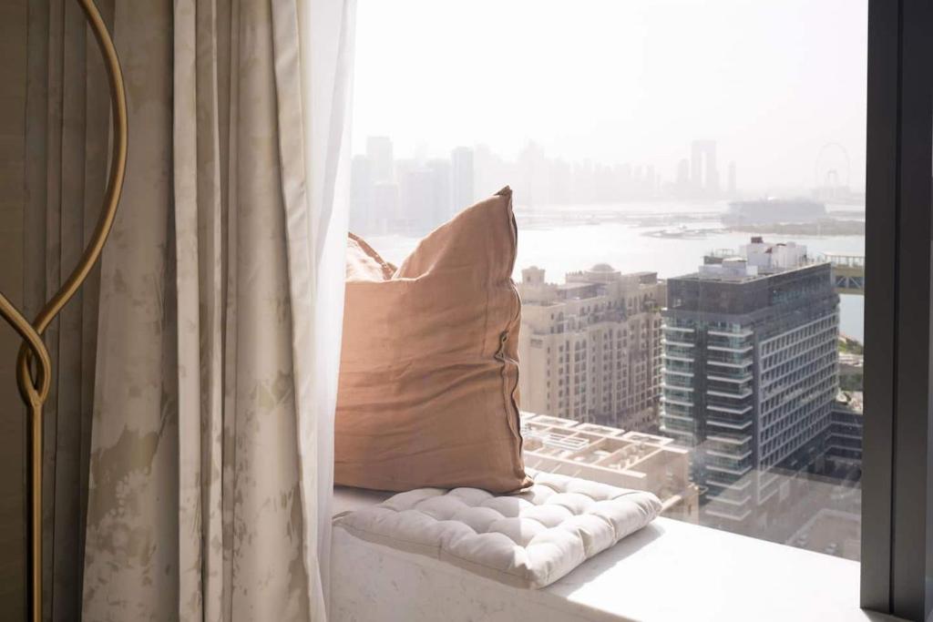 ein Kissen auf einem Fensterbrett mit Stadtblick in der Unterkunft Extravagant Palm Studio In 5-star Hoteloceanview in Dubai