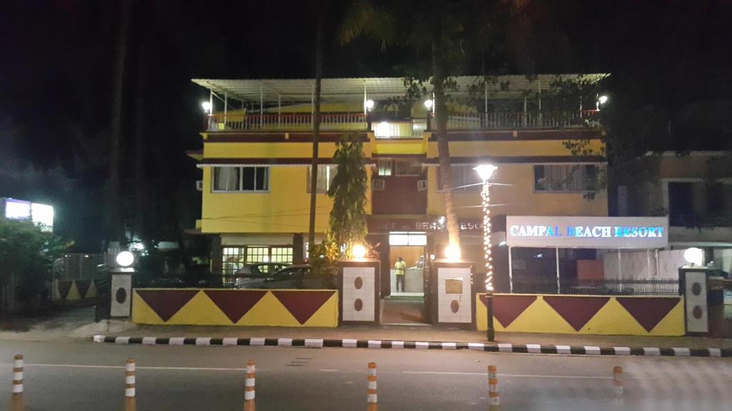 a tall yellow building at night with a street at Campal Beach Resort in Panaji