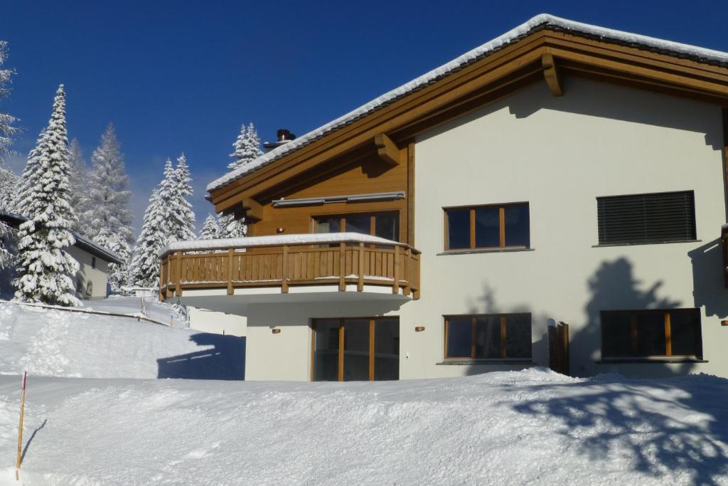ein Haus mit einer Terrasse im Schnee in der Unterkunft Alpine Lodge Parc Linard in Lenzerheide