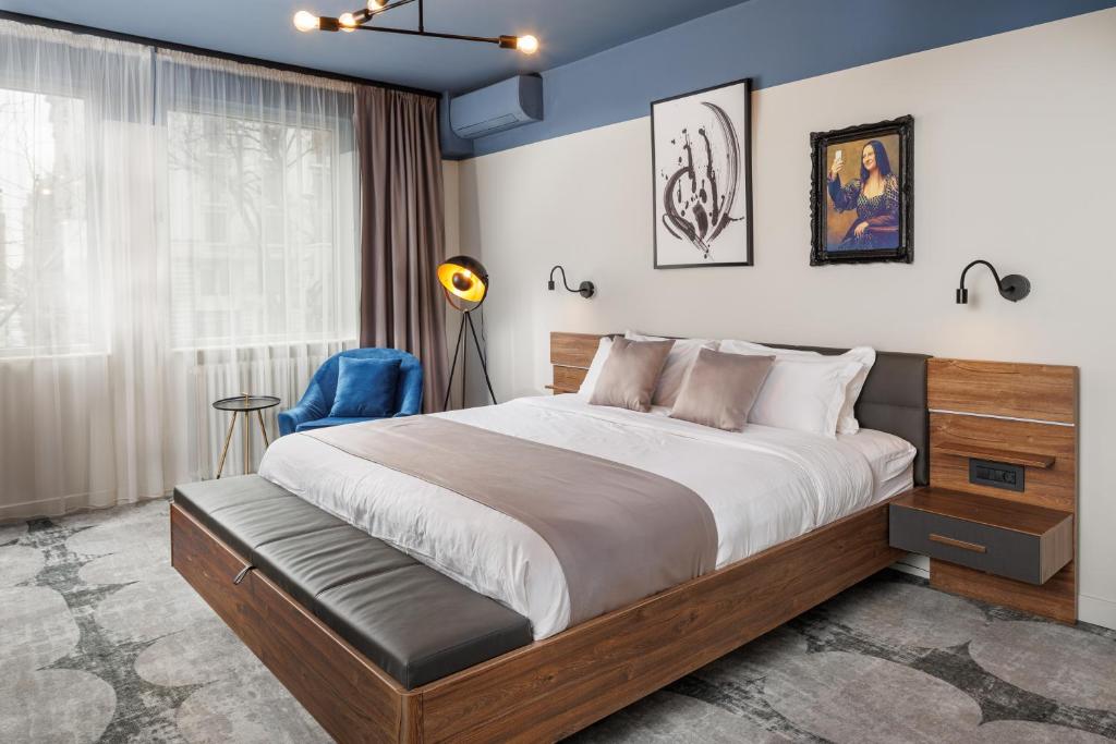 sypialnia z dużym łóżkiem i niebieską ścianą w obiekcie Bucharest Comfort Suites Hotel w Bukareszcie