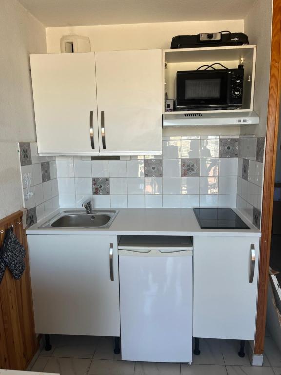 een witte keuken met een wastafel en een magnetron bij Appartement vue MER Valras plage in Valras-Plage
