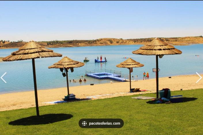 una playa con sombrillas y gente en el agua en Casa Amarela - Praias Alqueva, en Póvoa de São Miguel