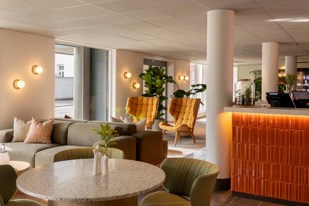 a lobby with a couch and a table and chairs at Comfort Hotel Park in Trondheim