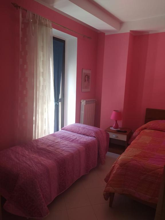 2 camas en una habitación con paredes rosas y ventana en Casa Italia en Oratino