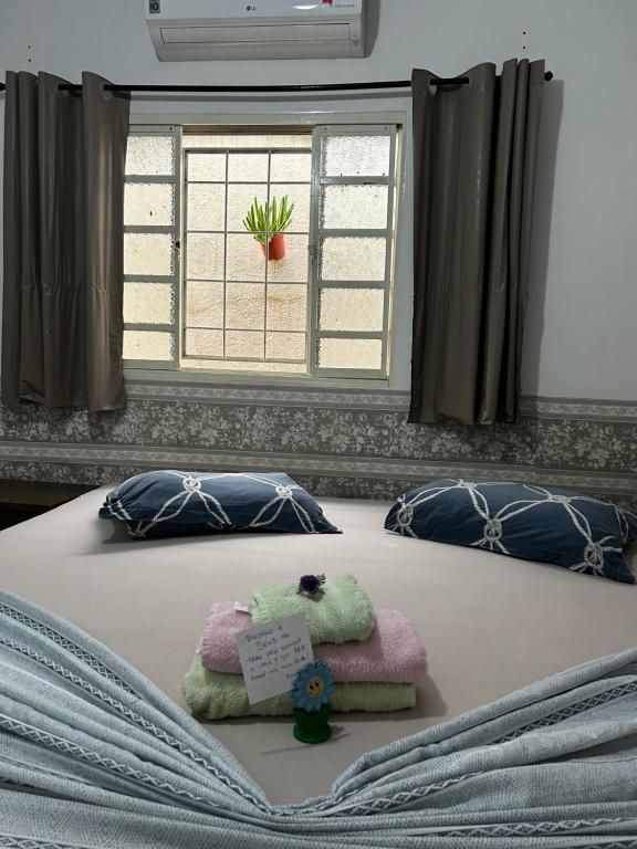 a bed with towels on it with a window at Pousada e Hotel Italian Garden House in Campo Grande