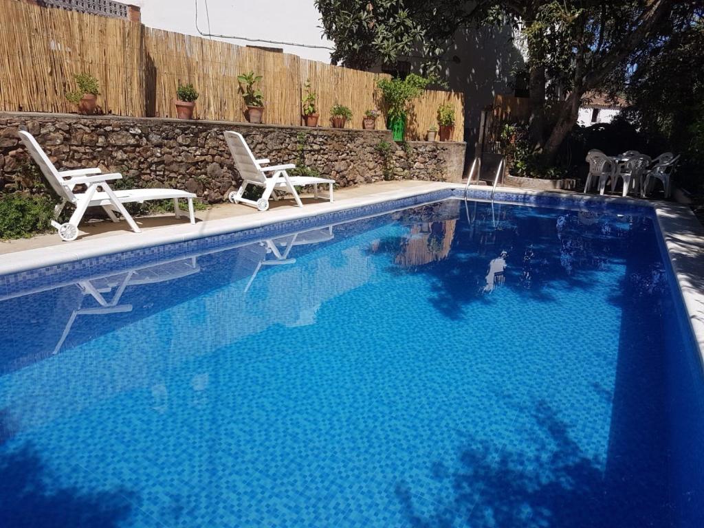 a large swimming pool with two chairs at Casa del escultor in Canaleja
