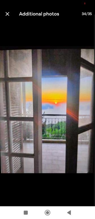 ein Fenster mit Blick auf den Sonnenuntergang, der durch ihn hindurch gesehen wird in der Unterkunft Ionian Lefkada Sunset House flyMeRachi40m in Exanthia