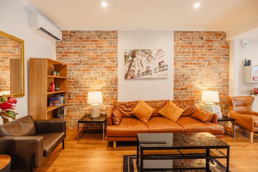 a living room with a couch and a brick wall at Newtown Cozy Stays in Sydney