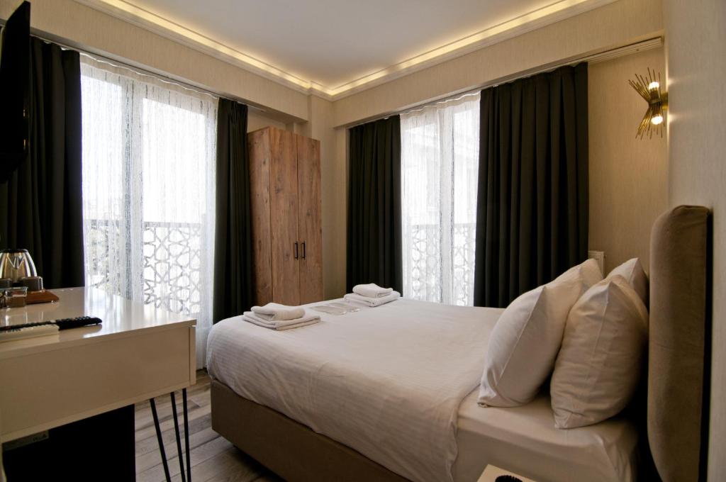 a bedroom with a bed and a desk and windows at SULTAN SÜLEYMAN APART HOTEL in Istanbul