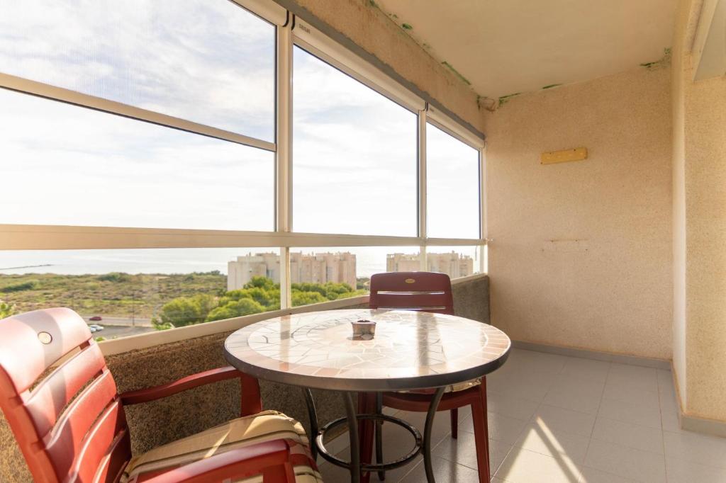 een tafel en stoelen in een kamer met een raam bij Vistas del Mar Oasis in El Campello