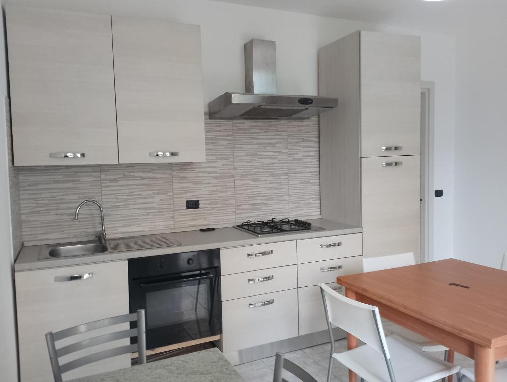 uma cozinha com armários brancos e uma mesa de madeira em Giallo Sole em Colleferro