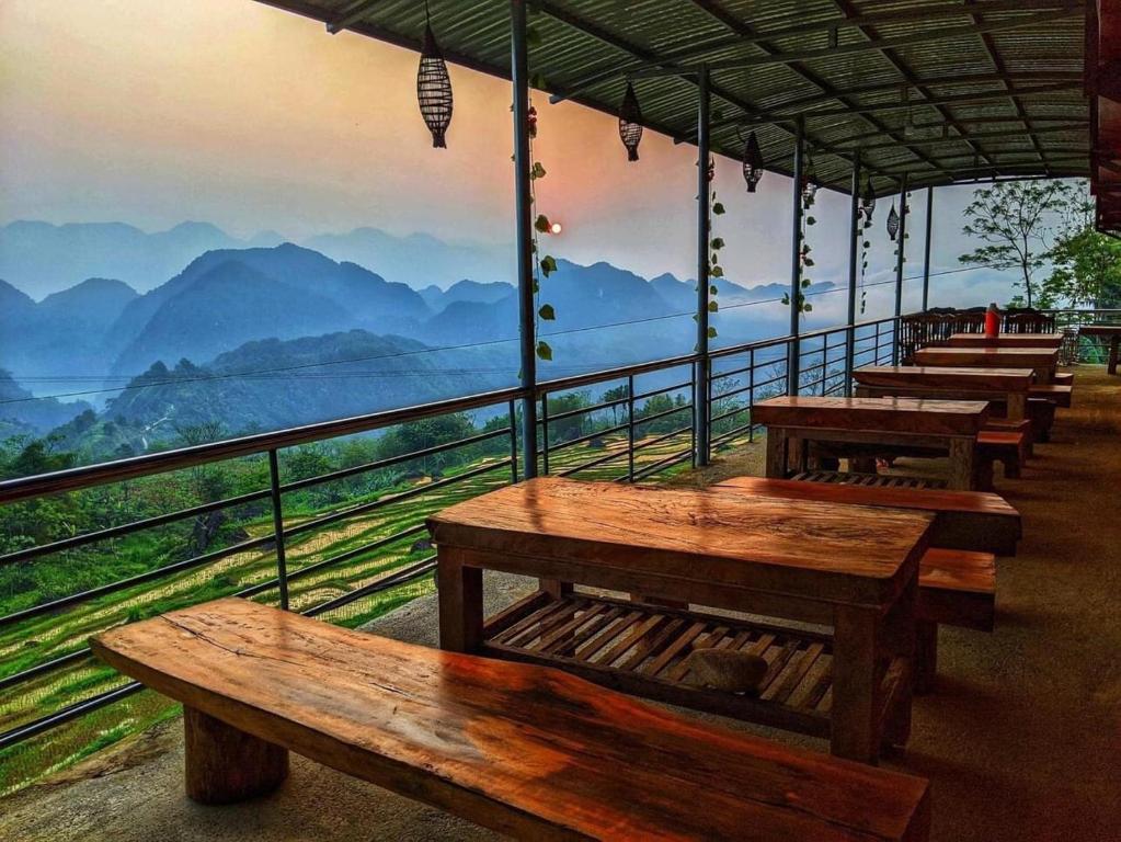 a row of wooden benches on a balcony with a view of mountains at OH Pu Luong Homestay in Hương Bá Thước