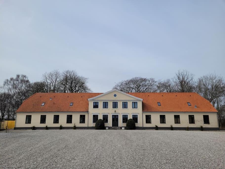 un gran edificio blanco con techo naranja en Privat lejlighed på landejendommen Frederiks-Eg, en Herlufmagle