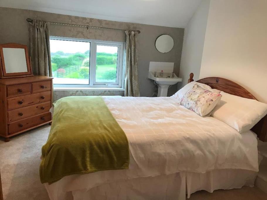 a bedroom with a large bed and a window at Moville Beach Townhouse on Wild Atlantic Way in Moville