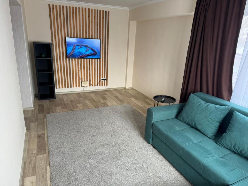 - un salon avec un canapé bleu et un tapis dans l'établissement Apartment on Protozanova 21, à Öskemen