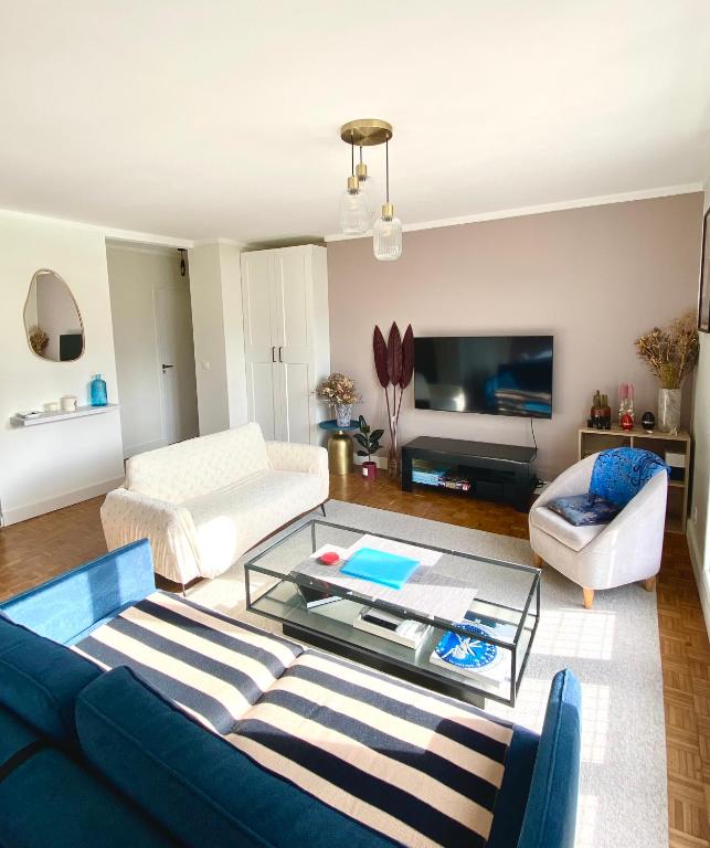 un salon avec un canapé bleu et une table en verre dans l'établissement Bel appartement de 77m2 à Boulogne au pied du métro, à Boulogne-Billancourt