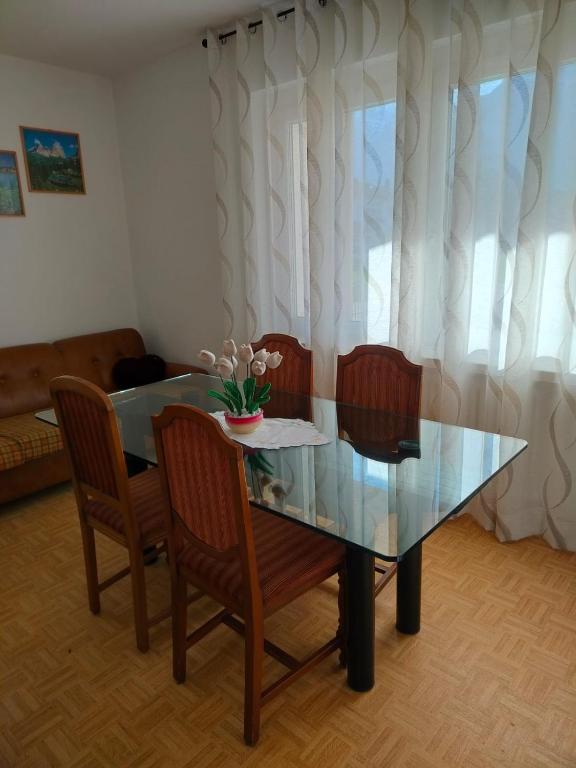 einen Glastisch mit Stühlen und eine Vase mit Blumen darauf in der Unterkunft Appartamento al Lago in Levico Terme