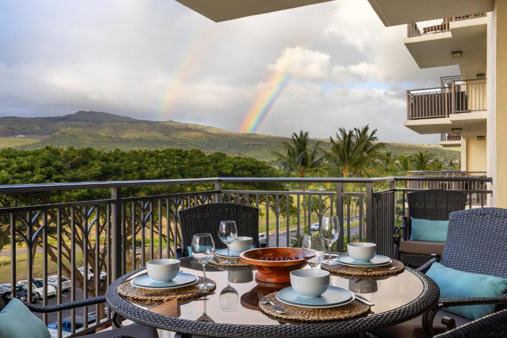 a table on a balcony with a rainbow in the background at Ko Olina Beach Villas B506 in Kapolei