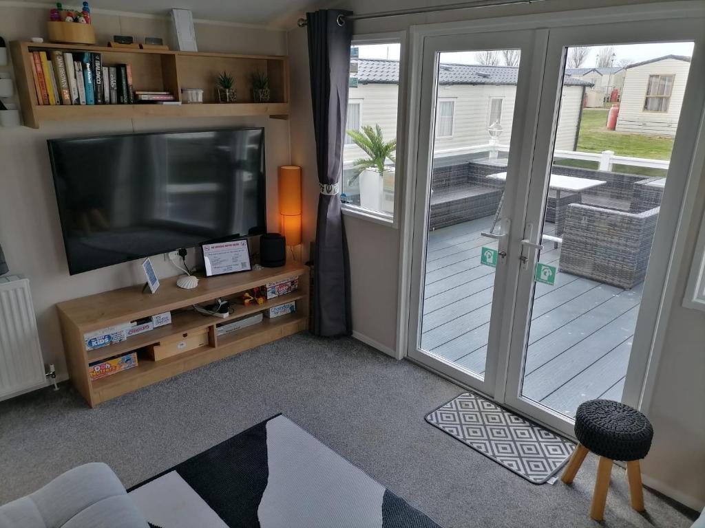 a living room with a television and a sliding glass door at The Beach - Large decking area in Kent