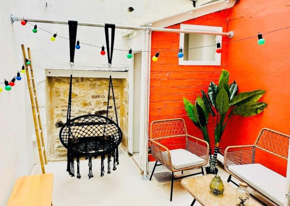 un porche avec une balançoire et un mur rouge dans l'établissement Maison au cœur du Vieux-Port de La Rochelle, à La Rochelle