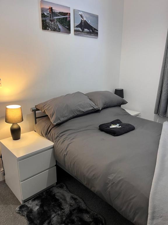 a bedroom with a bed and a night stand with a lamp at Meadow Street Rooms in Avonmouth