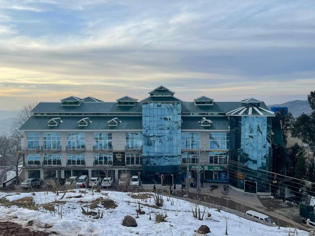 a large blue building with snow in front of it at Falettis Grand Hotel Murree in Murree