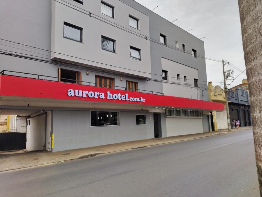 a building with a red sign on the side of it at Aurora Hotel in Ribeirão Preto