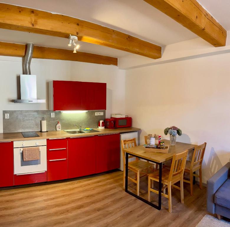 eine Küche mit roten Schränken und einem Holztisch in der Unterkunft Apartmán 2KK Sauna and Aromatherapy in Jihlava