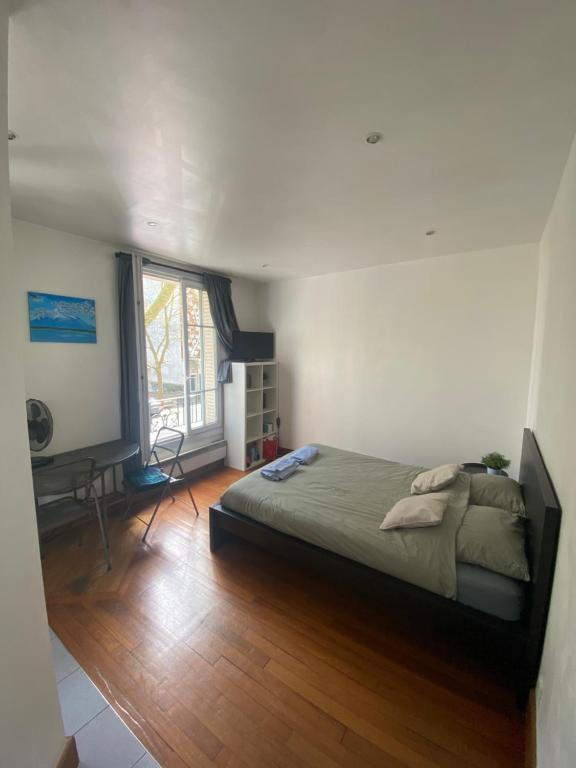 1 dormitorio con cama, escritorio y ventana en Studio Proche Paris en Chaville