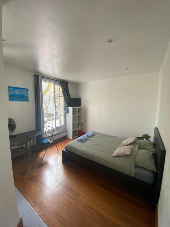 Un dormitorio con una cama y un escritorio y una ventana. en Studio Proche Paris, en Chaville