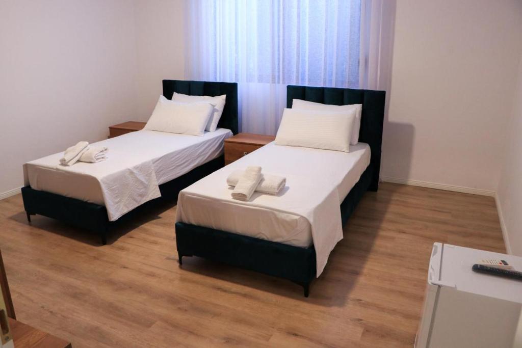 two beds in a room with wooden floors at Albora Guest House in Fier